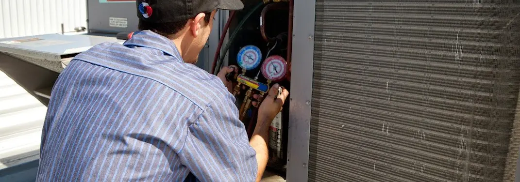 HVAC technician servicing a condenser unit in Geneva