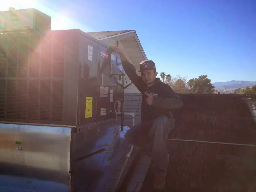 HVAC technician performing Heat Pump Repair on a rooftop unit in Geneva